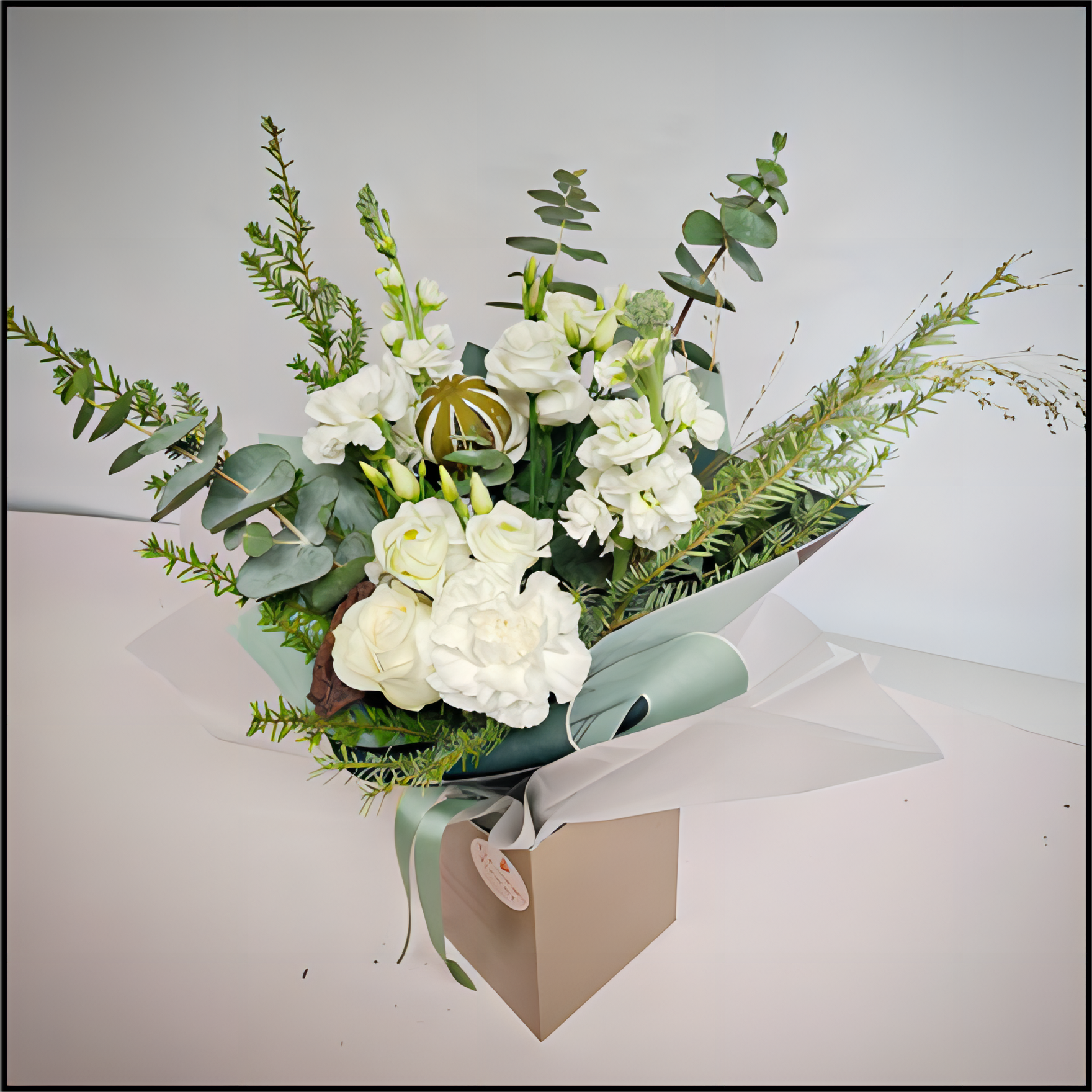 Bouquet of white flowers and greenery in a gift box 