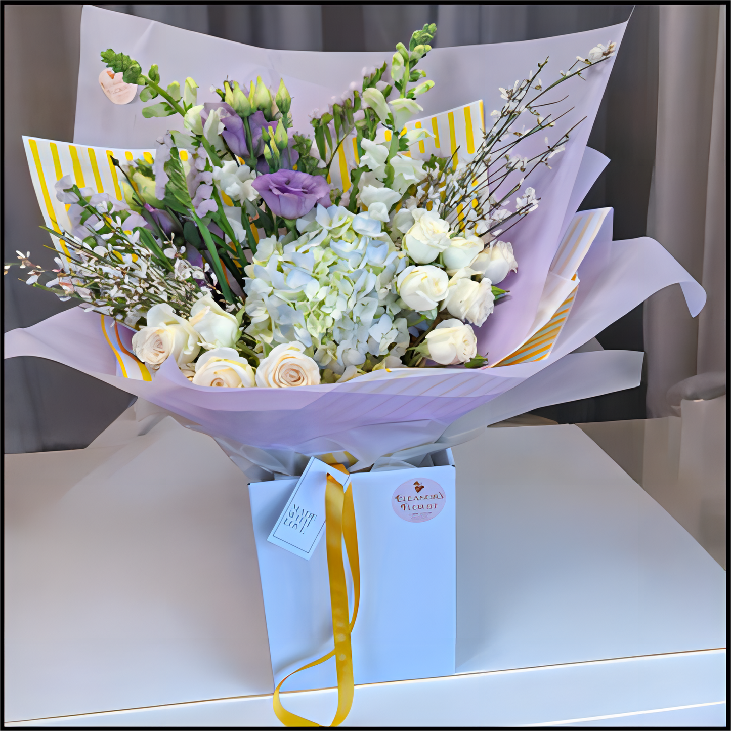 Bouquet of flowers wrapped in paper with a card in a cardboard box