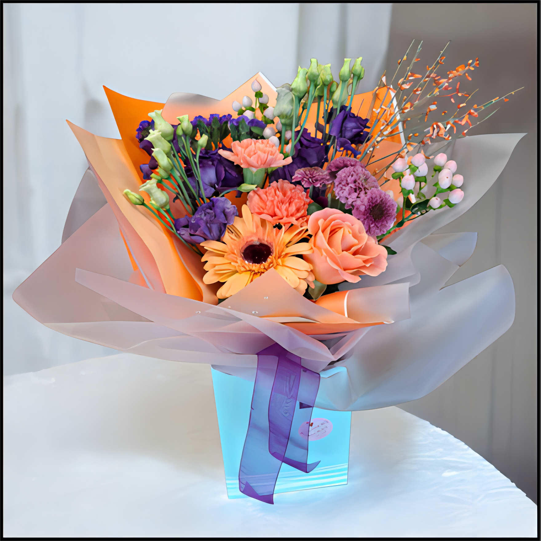 Bouquet of flowers wrapped in colourful paper with a purple ribbon, all in a cardboard box